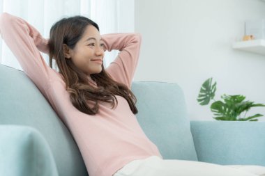 Neşeli genç Asyalı kadınlar kanepede oturur ve tatilin tadını çıkarırlar, eğlenirler, müzik dinlerler, kolunu kaldırırlar, en sevdiği şarkıyla dans ederler, güzel soundtrack 'lerin keyfini çıkarırlar, mutlu bir hayat, eğlence.