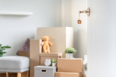 Moving house, relocation. The key was inserted into the door of the new house, inside the room was a cardboard box containing personal belongings and furniture. move in the apartment or condominium