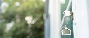 Landlord key for unlocking house is plugged into the door. Second hand house for rent and sale. keychain is blowing in the wind. mortgage for new home, buy, sell, renovate, investment, owner, estat