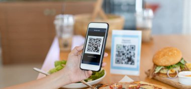 Woman use smartphone to scan QR code to pay in cafe restaurant with a digital payment without cash. Choose menu and order accumulate discount. E wallet, technology, pay online, credit card, bank app.