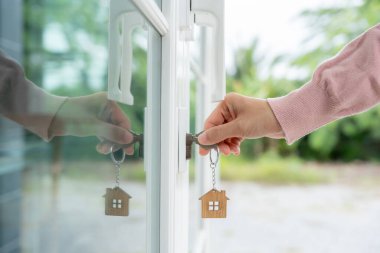 Evin kilidini açmak için ev sahibi anahtarı kapıya takılı. Kira ve satış için ikinci el ev. Sahibi yeni ev, satın al, sat, yenile, yatırım, sahip, mülk
