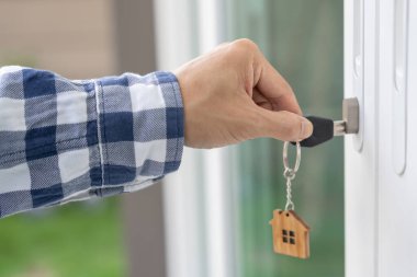 Evin kilidini açmak için ev sahibi anahtarı kapıya takılı. Kira ve satış için ikinci el ev. Sahibi el ile yeni ev için kapı ipoteğini açar, satın alır, satar, yeniler, yatırım, sahip, estat