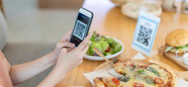 Woman use smartphone to scan QR code to pay in cafe restaurant with a digital payment without cash. Choose menu and order accumulate discount. E wallet, technology, pay online, credit card, bank app.