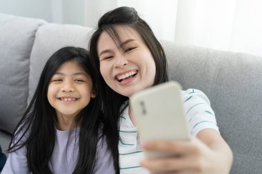 Taşınmak, taşınmak. Anne ve kızı gülümsüyor ve yeni eve taşındıktan sonra fotoğraf çekiyorlardı. Odanın içinde kişisel eşyalar ve mobilyalar olan bir karton kutu vardı. Yeni daireye taşın.