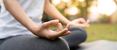 Kadın parkta meditasyon yapıyor. Sabahları egzersiz yapan Asyalı bir kadın. denge, dinlenme, rahatlama, sakinlik, sağlık, mutluluk, rahatlama, sağlıklı yaşam tarzı, stresi azaltma, huzur, tutum.