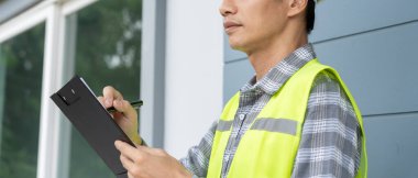 inspector or engineer is inspecting construction and quality assurance new house using a checklist. Engineers or architects or contactor work to build the house before handing it over to the homeowner