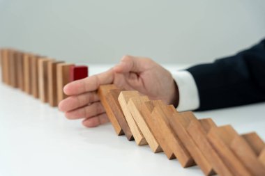 Domino 'yu elleri olan sigorta korur. İş adamı elleri iş krizinde domino taşlarının düşmesini durdurur. işletme risk denetimi ve planlama ve işletmeler sigorta işletmelerini önlemek için stratejiler.
