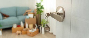 Moving house, relocation. The key was inserted into the door of the new house, inside the room was a cardboard box containing personal belongings and furniture. move in the apartment or condominiu