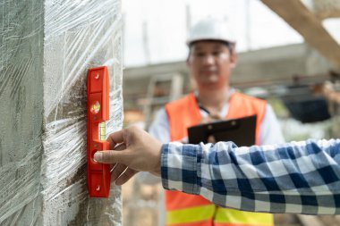 İrtibat kurucu veya mühendis, yeni ev inşaatını ve kalite güvencesini bir seviye kullanarak inceliyor. Mühendisler, mimarlar ya da irtibat görevlileri ev sahiplerine devretmeden önce evi inşa etmek için çalışıyorlar.