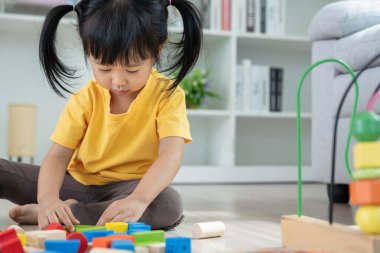 Mutlu Asyalı çocuk oyun oynuyor ve oyuncak bloklarını öğreniyor. Çocuklar evde çok mutlu ve heyecanlı. Çocuk oyun, etkinlik, gelişme ve dikkat eksikliği hiperaktivite bozukluğuyla çok iyi vakit geçiriyor