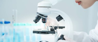 Bilimadamı ileri bilimsel laboratuvarda biyokimyasal örnekleri analiz ediyor. Tıbbi profesyonel kullanım mikroskobu virüsün mikrobiyolojik gelişimini gösteriyor. Fen laboratuvarında biyoteknoloji araştırması