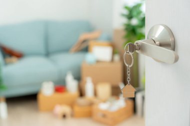 Moving house, relocation. The key was inserted into the door of the new house, inside the room was a cardboard box containing personal belongings and furniture. move in the apartment or condominium