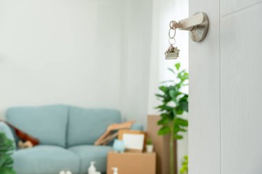 Moving house, relocation. The key was inserted into the door of the new house, inside the room was a cardboard box containing personal belongings and furniture. move in the apartment or condominiu