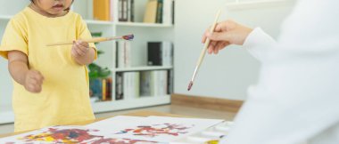 Mutlu Asyalı anne küçük kız için boya öğreniyor. Aile evde mutlu ve heyecanlı. Anne ve kızı birlikte vakit geçiriyorlar. Tatil, Faaliyet, Yönetici Fonksiyonu, IQ, EQ