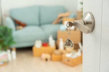 Taşınmak, taşınmak. Anahtar yeni evin kapısına yerleştirilmiş, odanın içinde kişisel eşyalar ve mobilyalar içeren bir karton kutu vardı. Daireye taşın ya da kondomini