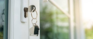 Landlord key for unlocking house is plugged into the door. Second hand house for rent and sale. keychain is blowing in the wind. mortgage for new home, buy, sell, renovate, investment, owner, estate