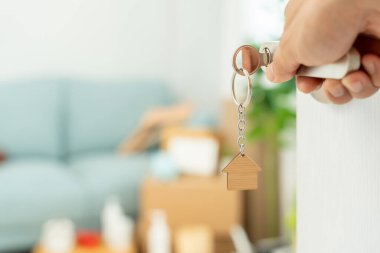Moving house, relocation. Couple hold key house keychain in new apartment, inside the room was a cardboard box containing personal belongings and furniture. move in the new apartment or condominium