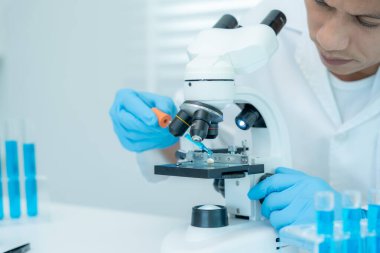 Bilimadamı ileri bilimsel laboratuvarda biyokimyasal örnekleri analiz ediyor. Tıbbi profesyonel kullanım mikroskobu virüsün mikrobiyolojik gelişimini gösteriyor. Fen laboratuvarında biyoteknoloji araştırması.