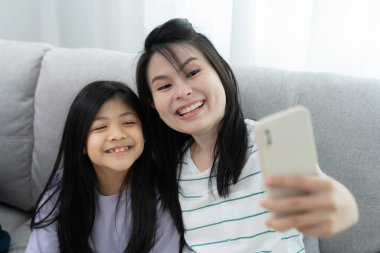 Taşınmak, taşınmak. Anne ve kızı gülümsüyor ve yeni eve taşındıktan sonra fotoğraf çekiyorlardı. Odanın içinde kişisel eşyalar ve mobilyalar olan bir karton kutu vardı. Yeni daireye taşın.