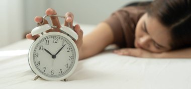 Tembel Asya 'lı genç kadın saat alarmını kapatıyor, bayan geç kalıyor ya da işe gidiyor ya da ders çalışıyor, uyuyakalıyor, sabahları uyanıyor, endişeleniyor, uykulu, geç kalmış, acele et.
