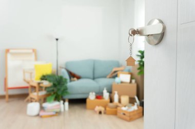 Moving house, relocation. The key was inserted into the door of the new house, inside the room was a cardboard box containing personal belongings and furniture. move in the apartment or condominium