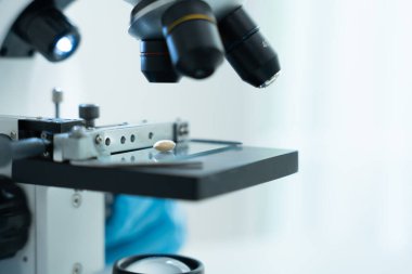 Bilimadamı ileri bilimsel laboratuvarda biyokimyasal örnekleri analiz ediyor. Tıbbi profesyonel kullanım mikroskobu virüsün mikrobiyolojik gelişimini gösteriyor. Fen laboratuvarında biyoteknoloji araştırması