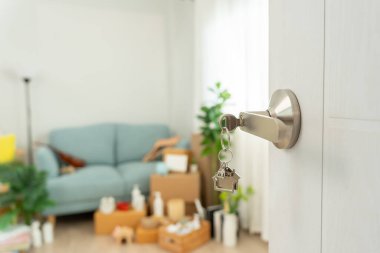 Moving house, relocation. The key was inserted into the door of the new house, inside the room was a cardboard box containing personal belongings and furniture. move in the apartment or condominiu