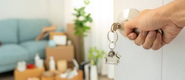 Taşınmak, taşınmak. Anahtar yeni evin kapısına yerleştirilmiş, odanın içinde kişisel eşyalar ve mobilyalar içeren bir karton kutu vardı. Daireye gir, afiş.