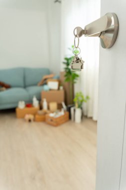 Moving house, relocation. The key was inserted into the door of the new house, inside the room was a cardboard box containing personal belongings and furniture. move in the apartment or condominium