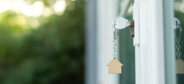 Landlord key for unlocking house is plugged into the door. Second hand house for rent and sale. keychain is blowing in the wind. mortgage for new home, buy, sell, renovate, investment, owner, estate