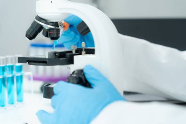Bilimadamı ileri bilimsel laboratuvarda biyokimyasal örnekleri analiz ediyor. Tıbbi profesyonel kullanım mikroskobu virüsün mikrobiyolojik gelişimini gösteriyor. Fen laboratuvarında biyoteknoloji araştırması.