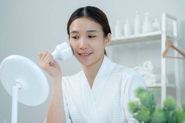 Güzel Asyalı kadınlar gözeneklerini sıkmak için aletler kullanır. Sağlıklı yüzler. Yüz bakımı ve tedavisi. Deri reklamı. Yüz kremi, kırışıklık önleyici, bebek yüzü, beyazlatma, nemlendirici, gözenek sıkılaştırıcı serum.