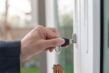 Evin kilidini açmak için ev sahibi anahtarı kapıya takılı. Kira ve satış için ikinci el ev. Sahibi yeni ev, satın al, sat, yenile, yatırım, sahip, mülk