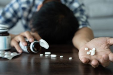Asyalı erkek aşırı dozda hap kullanıyor, stresli, üzgün, uyuşturucu bağımlısı, uyuşturucu bağımlısı, hasta, sağlıksız, mutsuz, intihar, depresyonda veya umutsuz, uyuşturucu bağımlısı, yaşam ve aile sorunları, motivasyonsuz