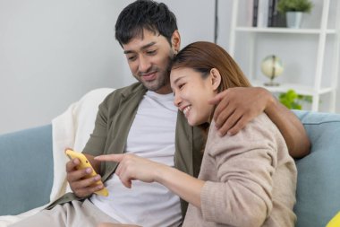 Çift evde online alışveriş yapmak için akıllı telefon kullanıyor. Ödeme detaylarıyla el ele tutuşan cep telefonu sayfa görüntüleme ve kredi kartı, evde kalmak, teknoloji, elektronik ticaret, internet, pazar yeri