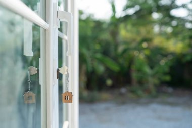 Landlord key for unlocking house is plugged into the door. Second hand house for rent and sale. keychain is blowing in the wind. mortgage for new home, buy, sell, renovate, investment, owner, estate