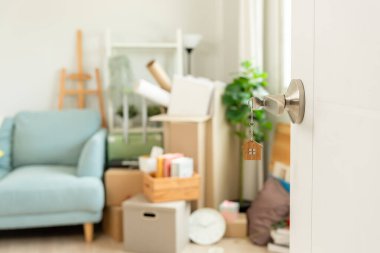 Moving house, relocation. The key was inserted into the door of the new house, inside the room was a cardboard box containing personal belongings and furniture. move in the apartment or condominium
