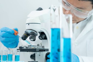 Bilimadamı ileri bilimsel laboratuvarda biyokimyasal örnekleri analiz ediyor. Tıbbi profesyonel kullanım mikroskobu virüsün mikrobiyolojik gelişimini gösteriyor. Fen laboratuvarında biyoteknoloji araştırması.