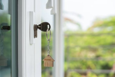 Evin kilidini açmanın anahtarı kapıya takılı. Kira ve satış için ikinci el ev. Anahtarlık rüzgarda savruluyor. Yeni ev için ipotek, satın alma, satma, yenileme, yatırım, sahip, mülk