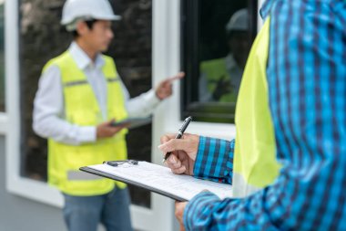 inspector or engineer is inspecting construction and quality assurance new house using a checklist. Engineers or architects or contactor work to build the house before handing it over to the homeowner