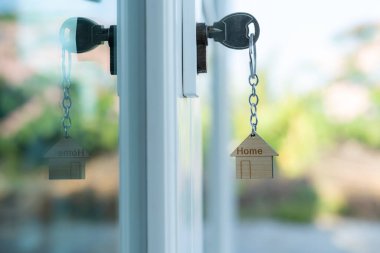 Evin kilidini açmanın anahtarı kapıya takılı. Kira ve satış için ikinci el ev. Anahtarlık rüzgarda savruluyor. Yeni ev için ipotek, satın alma, satma, yenileme, yatırım, sahip, mülk