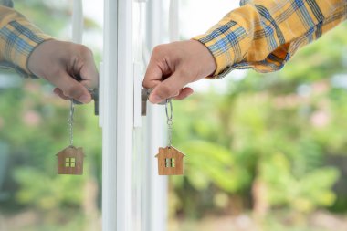 Evin kilidini açmak için ev sahibi anahtarı kapıya takılı. Kira ve satış için ikinci el ev. Sahibi yeni ev, satın al, sat, yenile, yatırım, sahip, mülk