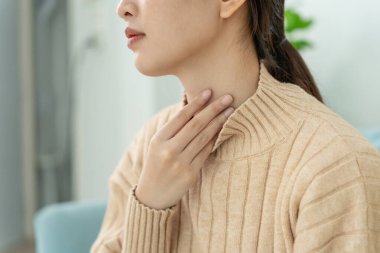 Asyalı kadın boğazı ağrıdığı için boynuna takıldı. Dişi bademcik iltihabı iltihaba neden olur. Su alarak, antibiyotik alarak, doktora, virüse, korona virüsüne, gribe, gribe danışarak tedavi olunur.