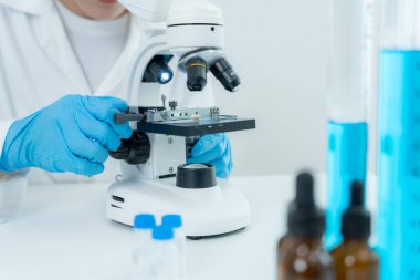 Bilimadamı ileri bilimsel laboratuvarda biyokimyasal örnekleri analiz ediyor. Tıbbi profesyonel kullanım mikroskobu virüsün mikrobiyolojik gelişimini gösteriyor. Fen laboratuvarında biyoteknoloji araştırması.