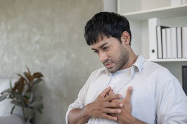 Göğüs kafesinde kalp krizi belirtileri var. Çok çalışan bir adamın göğüs ağrısı var. Kalp rahatsızlığı, sızıntı, genişleme, genişlemiş kalp, göğse acı verici bir ifadeyle bastırma.