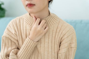 Asyalı kadın boğazı ağrıdığı için boynuna takıldı. Dişi bademcik iltihabı iltihaba neden olur. Su alarak, antibiyotik alarak, doktora, virüse, korona virüsüne, gribe, gribe danışarak tedavi olunur.