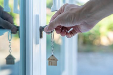 Evin kilidini açmak için ev sahibi anahtarı kapıya takılı. Kira ve satış için ikinci el ev. Sahibi el ile yeni ev için kapı ipoteğini açar, satın alır, satar, yeniler, yatırım, sahip, estat