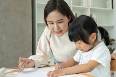 Mutlu Asyalı anne küçük kız için boya öğreniyor. Komik aile evde mutlu ve heyecanlı. Anne ve kızı birlikte vakit geçiriyorlar. Tatil, Etkinlik