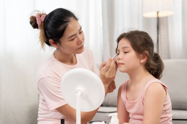 Anne mutlu çocuklar için makyaj yapıyor ve öğretmenlik yapıyor. Makyaj yapan kız. Aktivite ailesi, reklam, yaşam tarzı, kozmetik, makyaj malzemeleri, güzellik etkinliği, güzellik uzmanı, yetenek, aşk güzelliği.