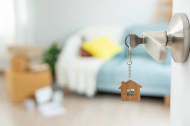 Moving house, relocation. The key was inserted into the door of the new house, inside the room was a cardboard box containing personal belongings and furniture. move in the apartment or condominium